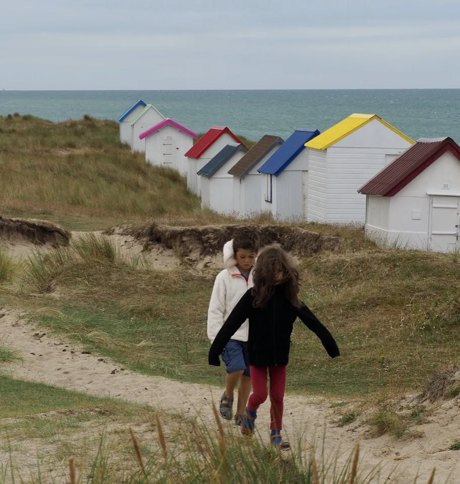 Famille de dos près des cabanes de plage du Cotentin