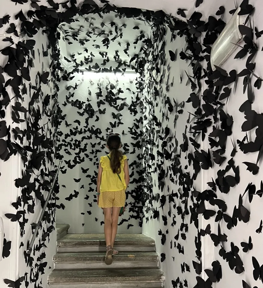 Besucherin von hinten in einer Installation aus schwarzen Schmetterlingen