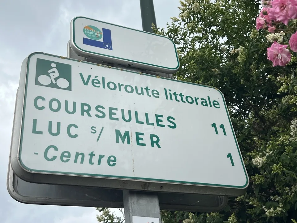 Panneau de la Véloroute littorale indiquant Courseulles à 11 km et Luc-sur-Mer centre à 1 km