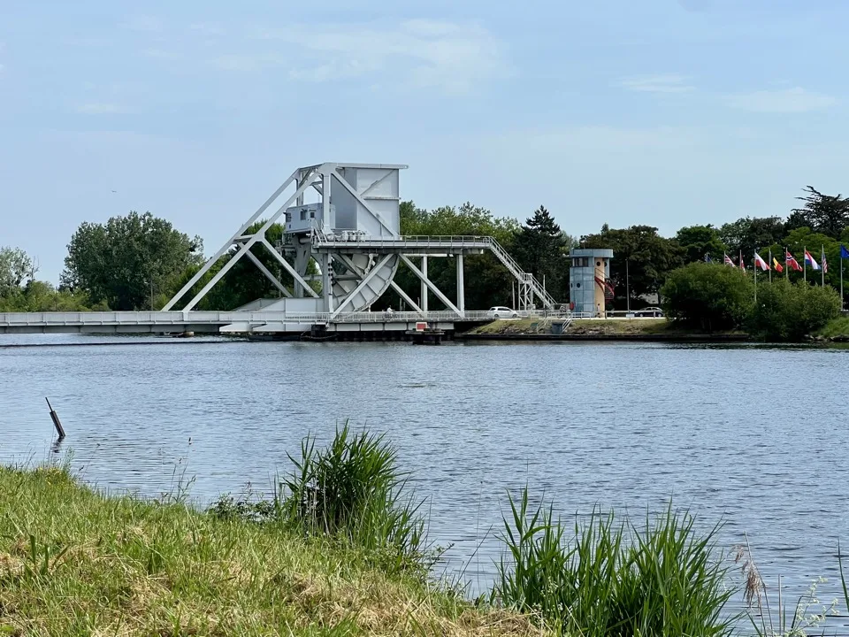 Pont basculant de Pegasus Bridge sur le canal de Caen à la mer, avec drapeaux internationaux sur la rive